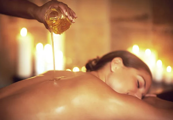 Onde o estresse termina e relaxamento começa.... Tiros de uma massagista derramando óleo em uma mulher antes de sua massagem. — Fotografia de Stock