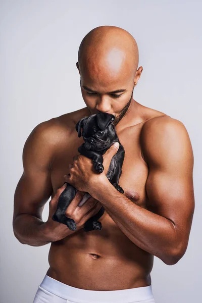 Estás en buenas manos, amiguito. Foto de un joven guapo posando con su adorable cachorro sobre un fondo gris. —  Fotos de Stock