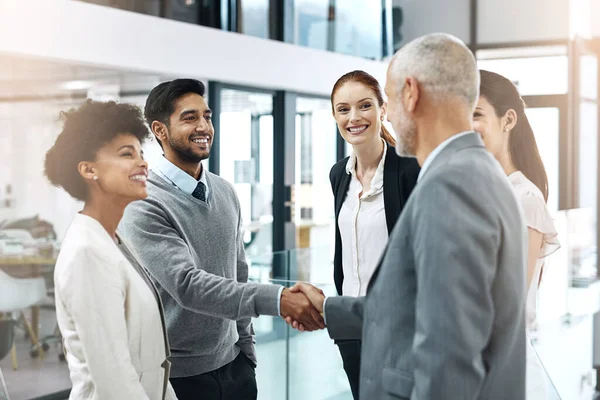 Conocer a su mentor. Disparo de dos hombres de negocios estrechando la mano mientras sus colegas miran. — Foto de Stock