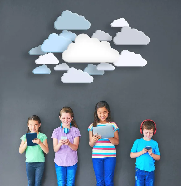 Los niños se mantienen conectados. Captura de estudio de niños usando tecnología inalámbrica con nubes sobre ellos sobre un fondo gris. —  Fotos de Stock