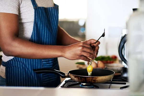 Los huevos fritos son sus favoritos. Recortado disparo de un hombre irreconocible freír huevos mientras hace el desayuno en su cocina en casa. — Foto de Stock