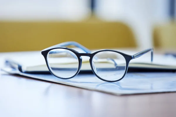 Être visionnaire est une grande force. Prise de vue de lunettes et de documents sur un bureau dans un bureau vide pendant la journée. — Photo