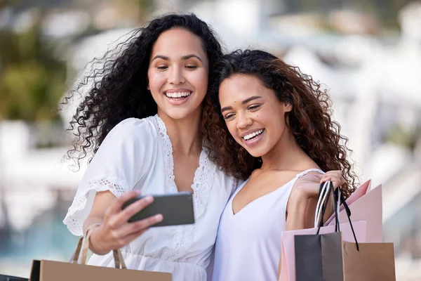 Gli amici non lasciano che gli amici facciano acquisti da soli. Scatto di due giovani donne che scattano selfie mentre fanno shopping su uno sfondo urbano. — Foto Stock