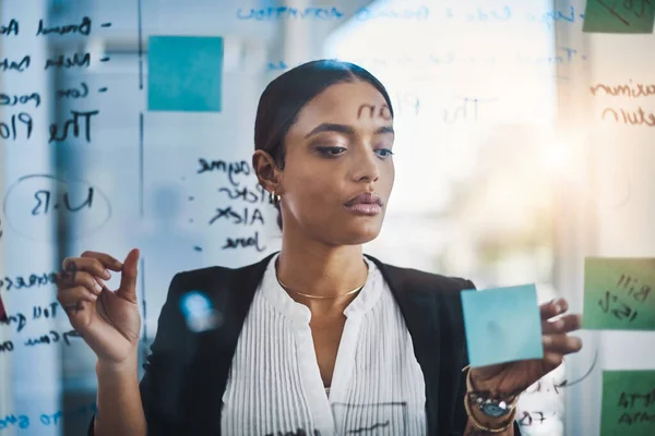 Ela faz sempre um plano. Tiro de uma mulher de negócios jovem brainstorming notas em uma parede de vidro em um escritório. — Fotografia de Stock