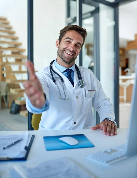 Have a seat and lets discuss your health. Portrait of a young doctor extending a handshake in his office. — Foto de Stock