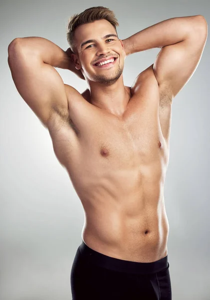 Zien deze spieren er goed uit bij mij? Studio portret van een gespierde jongeman poseren tegen een grijze achtergrond. — Stockfoto