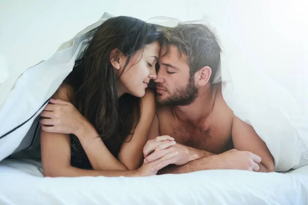 I am more in love with you than ever. Shot of a young couple having an intimate moment under the covers. — Stock Photo, Image