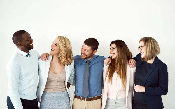 Deze groep is heel dichtbij. Studio-opname van een groep collega 's die met hun armen om elkaar heen staan tegen een witte achtergrond. — Stockfoto