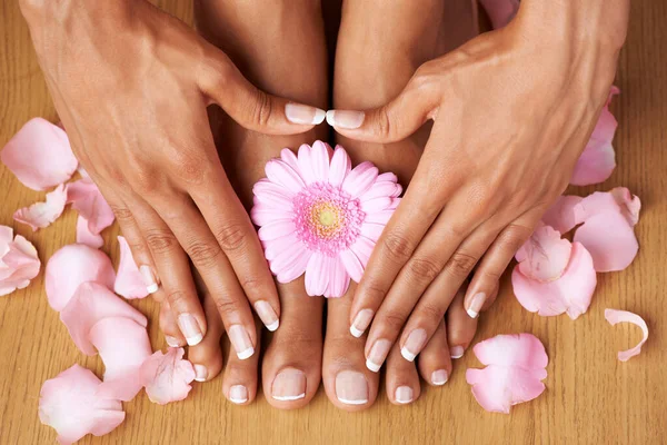 Beauté florale. Vue recadrée des mains sur les pieds parfaitement pédicurés avec des fleurs tout autour. — Photo