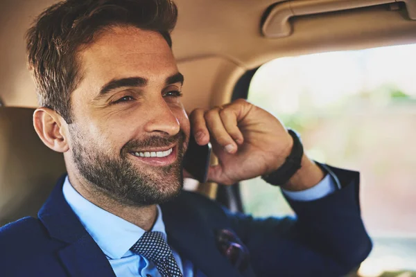A falar de negócios como um profissional. Tiro de um jovem empresário alegre falando em seu celular enquanto está sentado nas costas de um carro. — Fotografia de Stock