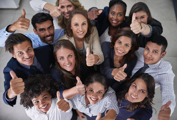 This team is all about positive attitudes. High angle portrait of a group of coworkers showing a thumbs up in the office.