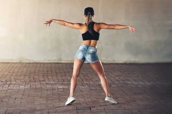 Hon får tillbaka spåret. Rearview skott av en kvinnlig street dansare tränar ute i staden. — Stockfoto