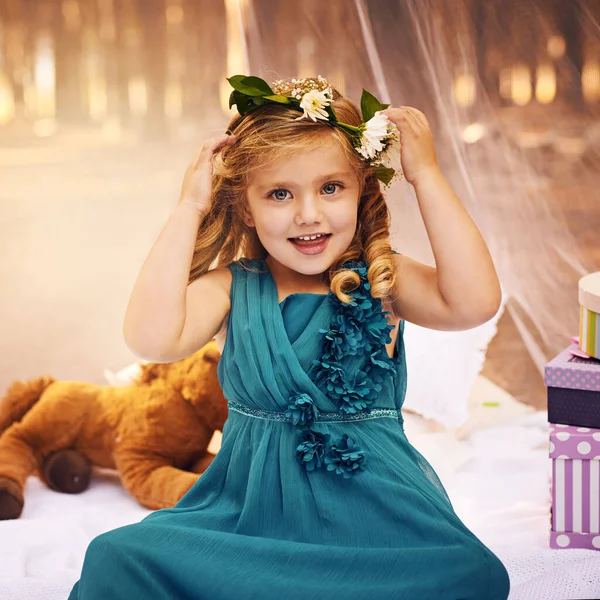 Las flores son importantes para una princesa de hadas. Foto de una niña feliz mirando a la cámara y tocando una corona de flores en su cabeza mientras estaba sentada afuera en el bosque. —  Fotos de Stock