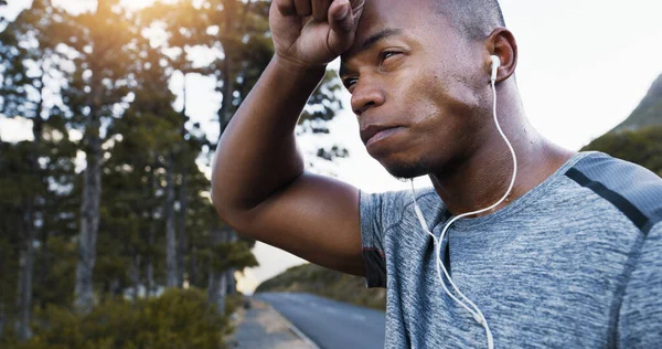 Als je niet zweet, werk je niet hard genoeg. Opname van een sportieve jongeman die een pauze neemt terwijl hij buiten traint. — Stockfoto