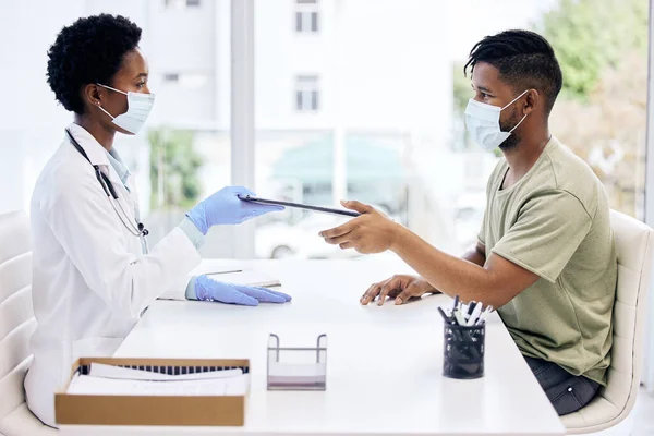 Please fill this out. Cropped shot of an attractive young female doctor handing a clipboard to a male patient during a consult. — Foto Stock