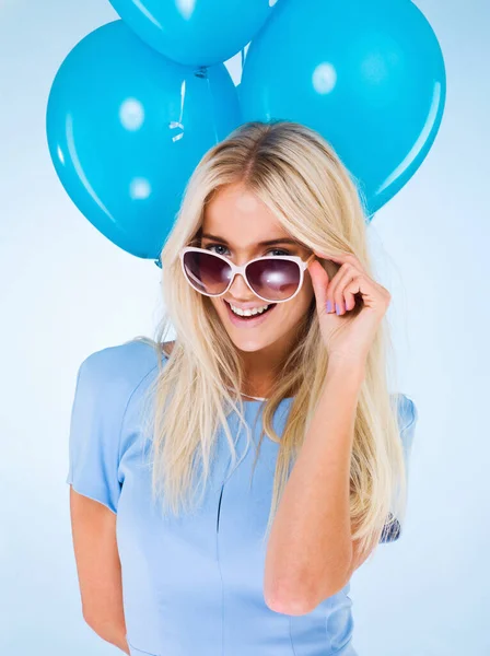Vem juntar-te à festa. Uma bela jovem mulher em óculos de sol posando com balões. — Fotografia de Stock