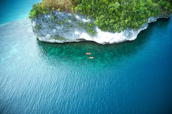 Лучше всего путешествовать по острову на каноэ. Высокий угол съемки двух авантюрных молодых пар каноэ вместе в красивых океанах Индонезии. — стоковое фото
