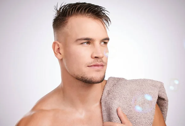 Looking good from every angle. Shot of a young man holding a towel against a grey background. — Stock Photo, Image