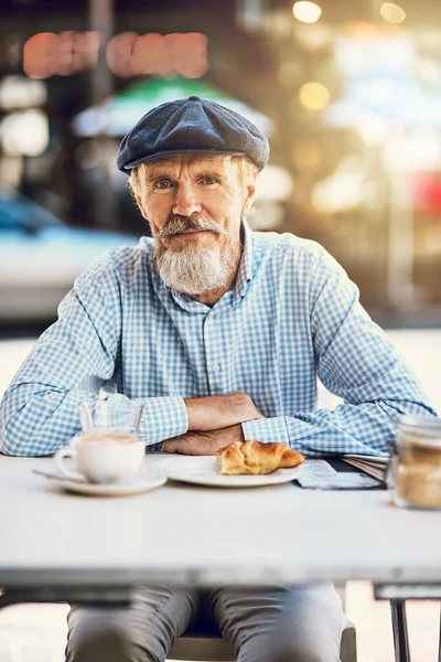Уход на пенсию тебе идет. Портрет счастливого пожилого человека, наслаждающегося чашечкой кофе в кафе на тротуаре. — стоковое фото