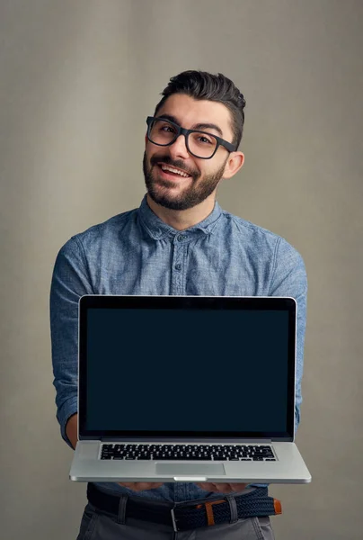 Seu site de negócios ficaria ótimo aqui. Retrato de estúdio de um jovem segurando um laptop contra um fundo cinza. — Fotografia de Stock