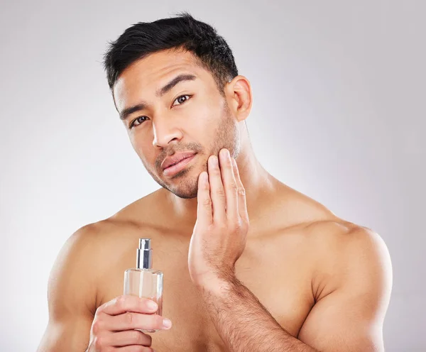 Erfolgsgeheimnis beginnt mit der Suche nach dem eigenen Duft. Studioporträt eines gutaussehenden jungen Mannes, der Aftershave anwendet. — Stockfoto
