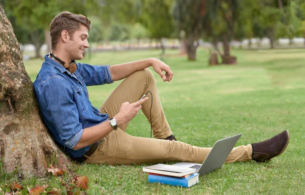 どの図書館よりもいい。ノートパソコンで公園で勉強してるハンサムな若者のショット. — ストック写真