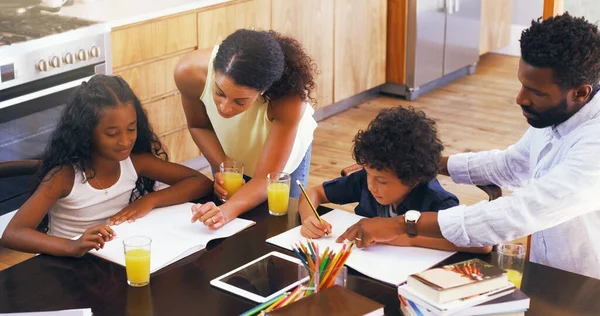 Desempenhe um papel ativo em seus trabalhos de casa de crianças. Tiro recortado de pais ajudando seus dois filhos com seus trabalhos escolares em casa. — Fotografia de Stock