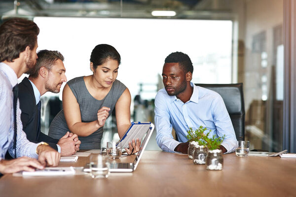 Она знает свое дело. Снимок группы корпоративных коллег, разговаривающих вместе за цифровым планшетом в офисе.