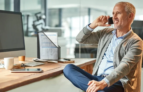 Es genial con los clientes. Fotografía de un hombre de negocios maduro hablando por teléfono mientras estaba sentado en su escritorio en una oficina. —  Fotos de Stock