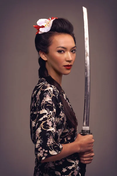 Bir kılıçla rakipsiz. Samuray kılıcı tutan çekici genç bir kadının stüdyo fotoğrafı.. — Stok fotoğraf