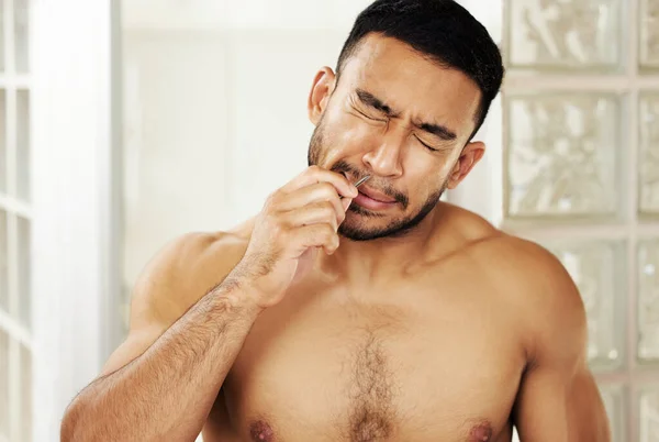 Credo che dovrei investire in un trimmer per il naso. Colpo ritagliato di un giovane uomo che usa pinzette per strappare i peli del naso. — Foto Stock