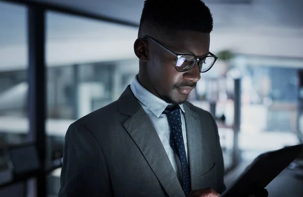 Hij heeft altijd oog voor de laatste zakelijke updates. Foto van een jonge zakenman met een digitale tablet in een kantoor 's nachts. — Stockfoto