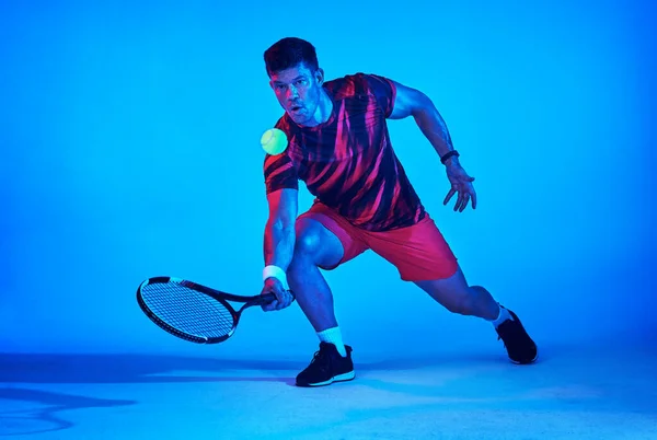 Laat de racket het woord doen. Blauw gefilterd beeld van een tennisspeler in de studio. — Stockfoto