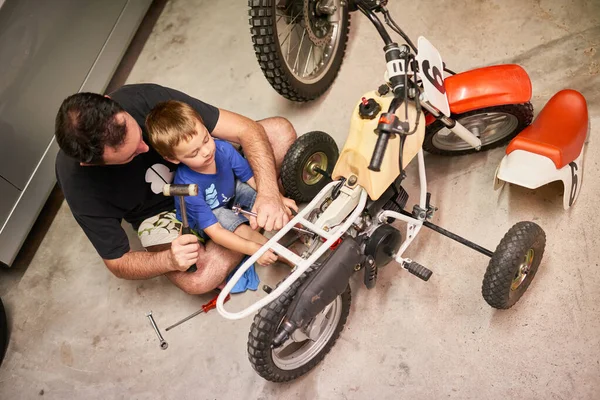 Je fixe leur jeu de roues le plus cool. Prise de vue d'un père et d'un fils réparant un vélo dans un garage. — Photo