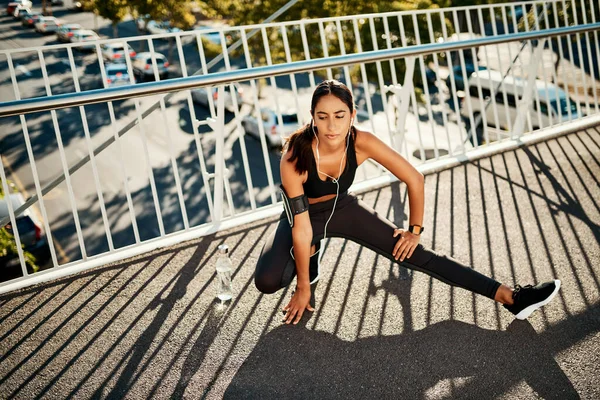 Time to up those fitness levels. Shot of a sporty young woman stretching before her run in the city. — Stock Photo, Image