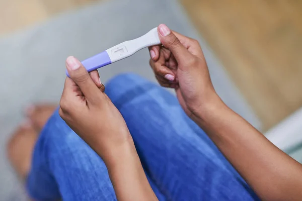 Bueno, esto es una sorpresa. Fotografía de una mujer no identificable que sostiene una prueba de embarazo mientras está sentada en su baño. — Foto de Stock