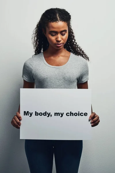 Mijn lichaam, mijn leven, mijn keuze. Studio shot van een aantrekkelijke jonge vrouw houden bordje dat leest Mijn lichaam, mijn keuze tegen een grijze achtergrond. — Stockfoto