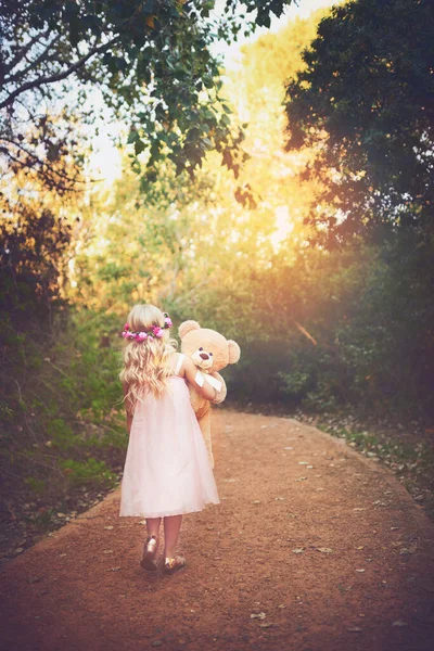 Je me demande où ça mène. Tourné d'une petite fille méconnaissable marchant avec son ours en peluche au milieu d'un chemin de terre. — Photo