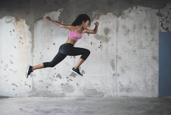 Повернення в дію. Повнометражний знімок спортивної молодої спортсменки, що стрибає в повітрі проти стіни на відкритому повітрі . — стокове фото