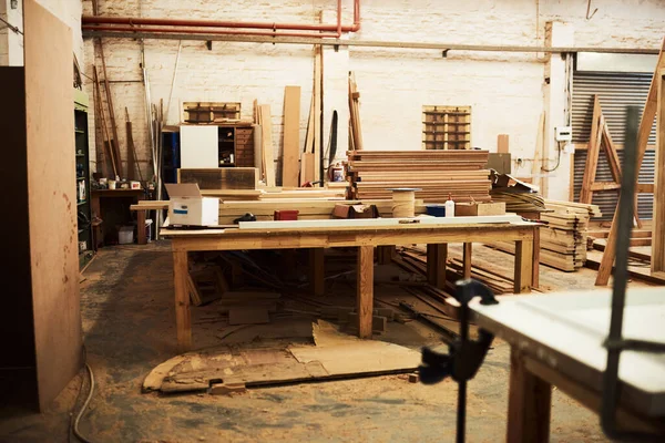 Qui e 'dove avviene tutta la magia. Natura morta ripresa di tavoli da lavoro e mucchi di legno all'interno di una falegnameria. — Foto Stock