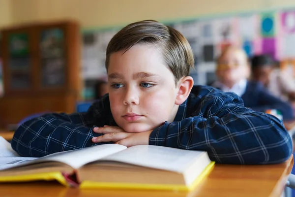 This is so boring. Shot of a young boy sitting in his classroom at school and feeling bored. — Stock Photo, Image