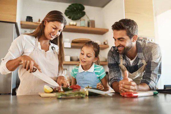 Apprendre des meilleurs. Tourné d'une jeune famille heureuse cuisiner ensemble dans leur cuisine à la maison. — Photo