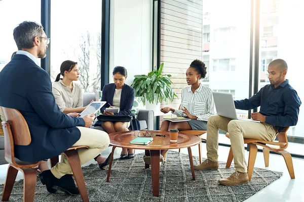 Hon kommer med nya idéer till bordet. Skjuten av en grupp arbetskamrater som talade tillsammans vid ett möte på ett kontor. — Stockfoto