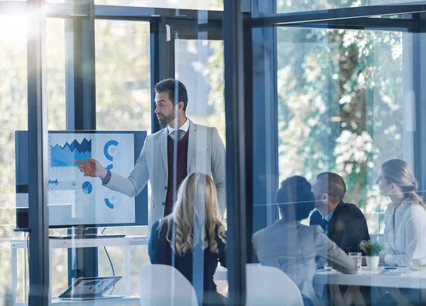 Teamarbeit teilt die Aufgabe und multipliziert den Erfolg. Aufnahme eines Geschäftsmannes, der einer Gruppe von Geschäftsleuten Informationen auf einem Monitor im Büro präsentiert. — Stockfoto
