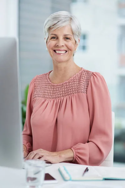 Shes enjoying herself at work today. Portrait of a mature businesswoman working on a computer in her office. — Stock Photo, Image