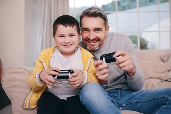 Mai un perdente dolorante. Girato di un padre e un figlio che giocano ai videogiochi mentre si legano sul divano a casa. — Foto Stock