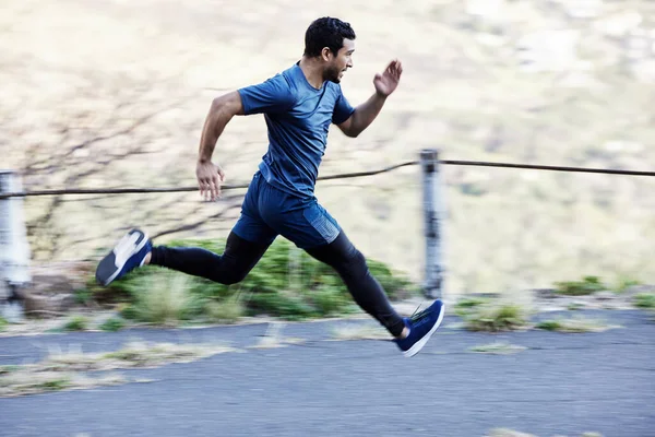 Een serieuze snelheid. Full length shot van een knappe jonge mannelijke atleet uit voor een run op de weg. — Stockfoto