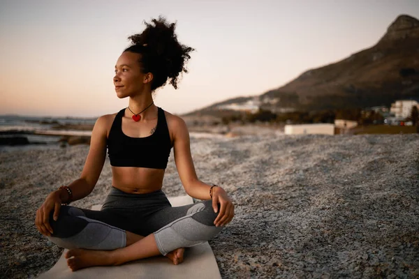 Це ідеальне місце для йоги. Повнометражний знімок привабливої молодої жінки, що практикує йогу на пляжі під час заходу сонця . — стокове фото