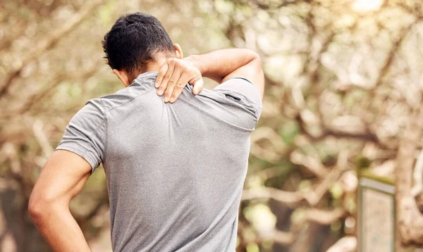 No viniste tan lejos sólo para llegar tan lejos. Vista trasera de un hombre irreconocible que experimenta dolor de cuello mientras hace ejercicio en la naturaleza. —  Fotos de Stock