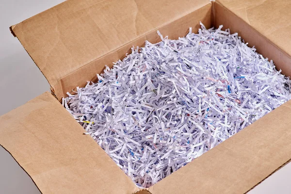 Shredded paper is great for packing. Studio shot of shredded paper in a cardboard box against a grey background. — Stock Photo, Image